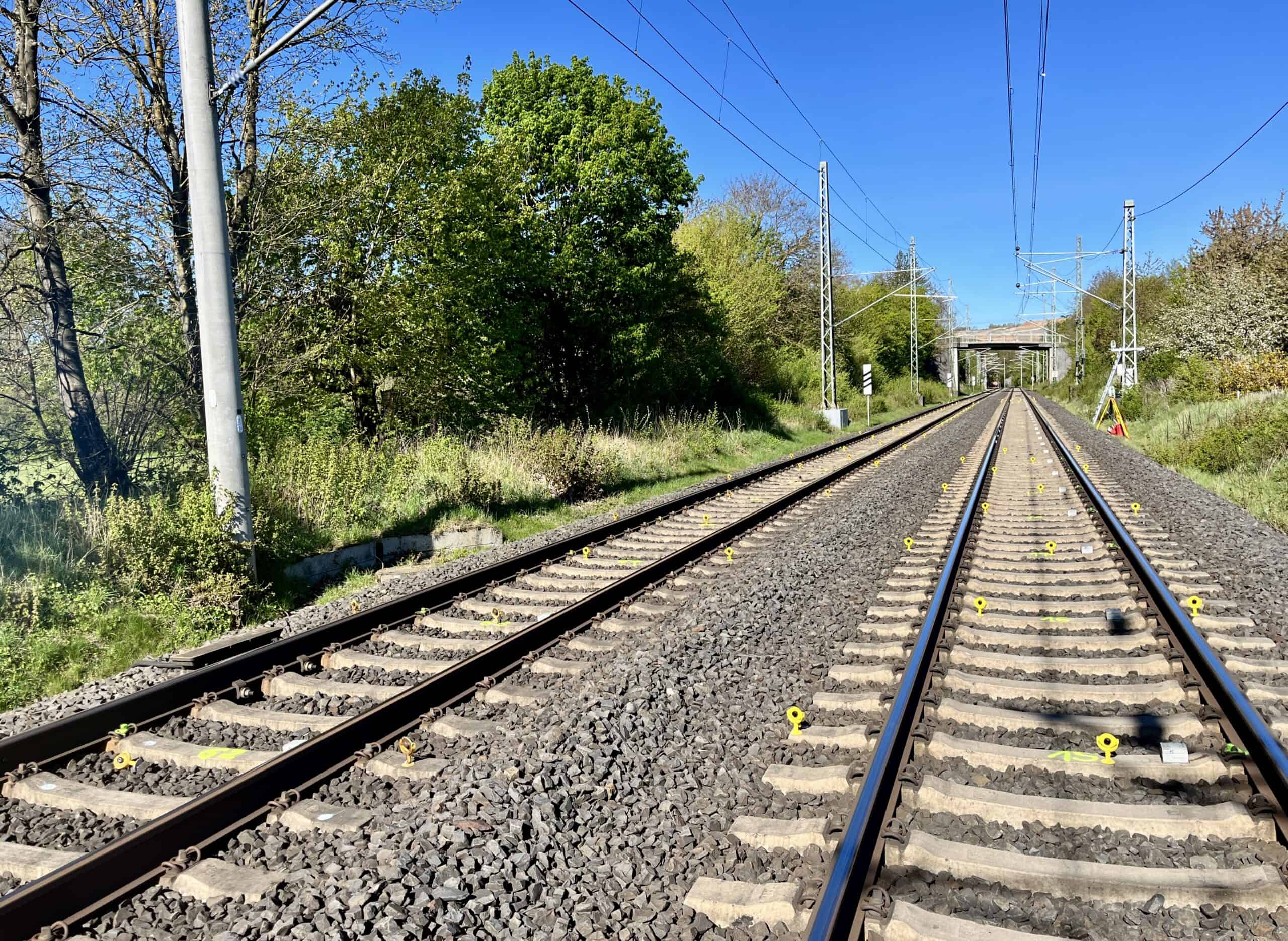 Bahnstrecke mit Messprismen für das Gleismonitoring, im Hintergrund ein Tachymeter-Standpunkt von intermetric bei Möckmühl