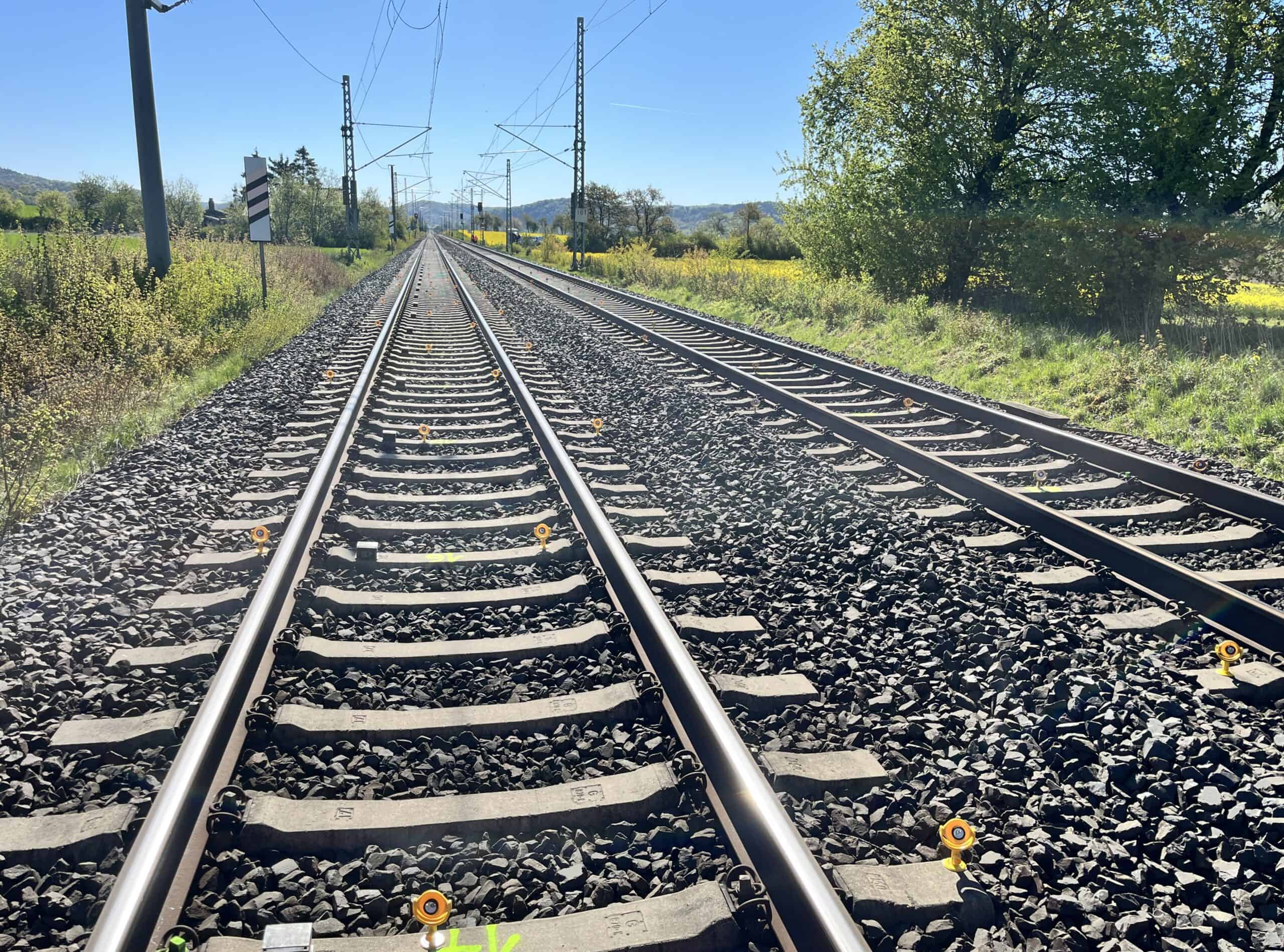 Blick entlang der Bahnstrecke mit Messprismen an den Schienen, überwacht per Gleismonitoring nahe Möckmühl