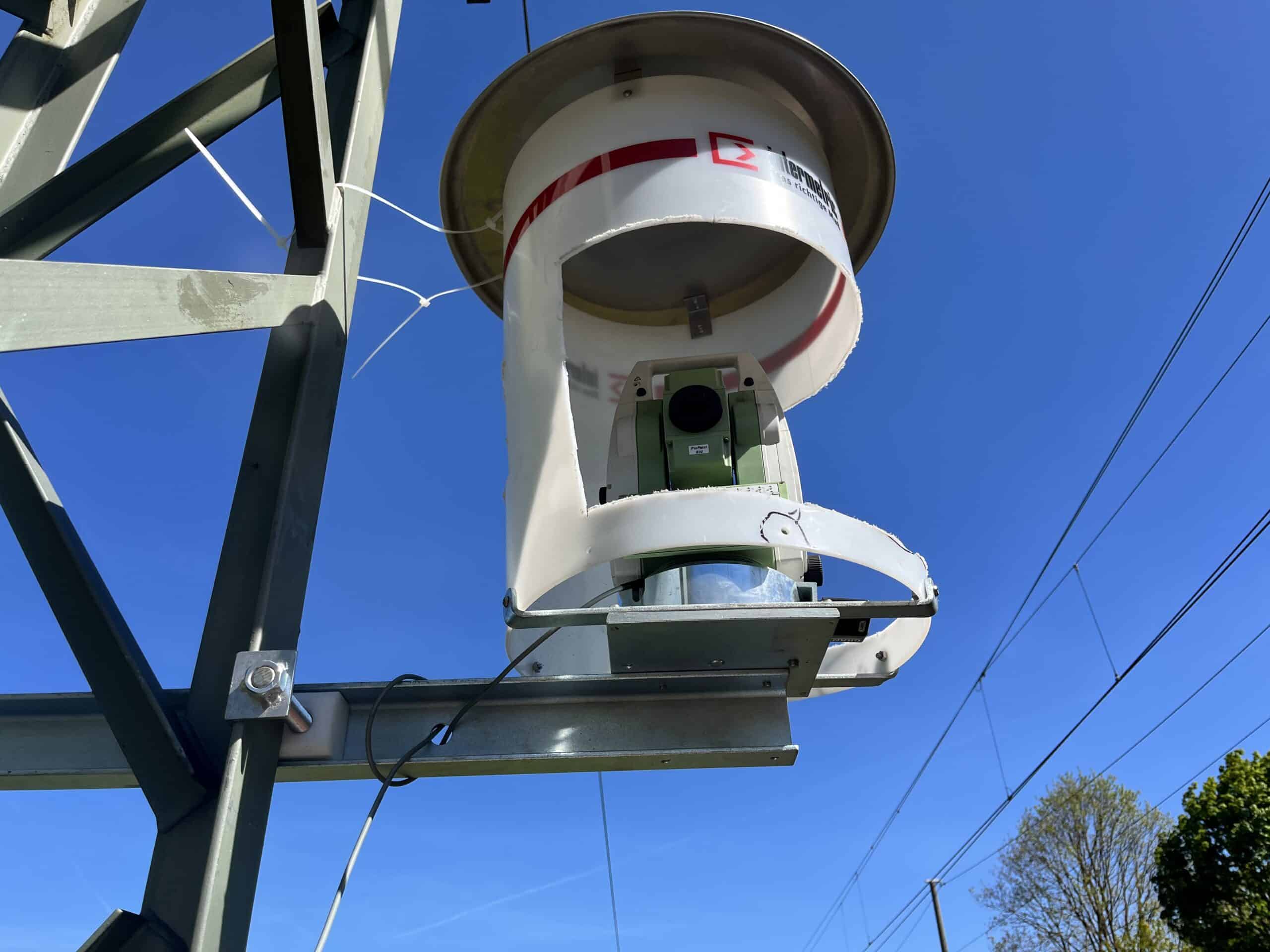 Tachymeter im weißen intermetric-Schutzgehäuse am Standpunkt neben dem Gleis, Kernsensor des Gleismonitorings bei SuedLink
